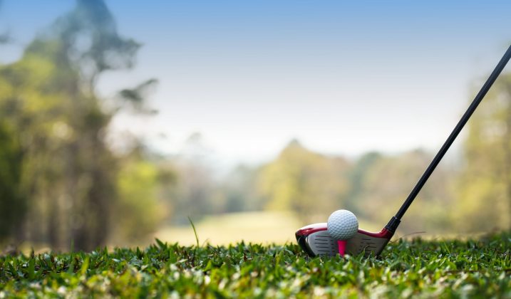 Golf clubs and golf balls on a green lawn in a beautiful golf course with morning sunshine. Golf clubs and golf balls on a green lawn in a beautiful golf course with morning sunshine. golf ball on green grass ready to hit on golf course background.